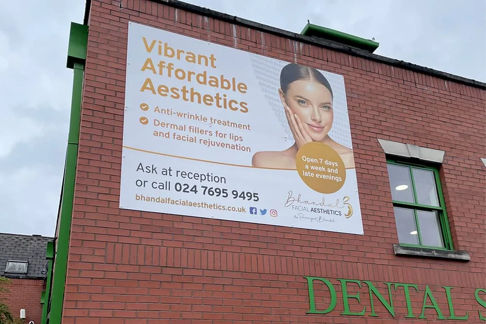 Large wall-mounted banner for an aesthetics clinic on a brick elevation