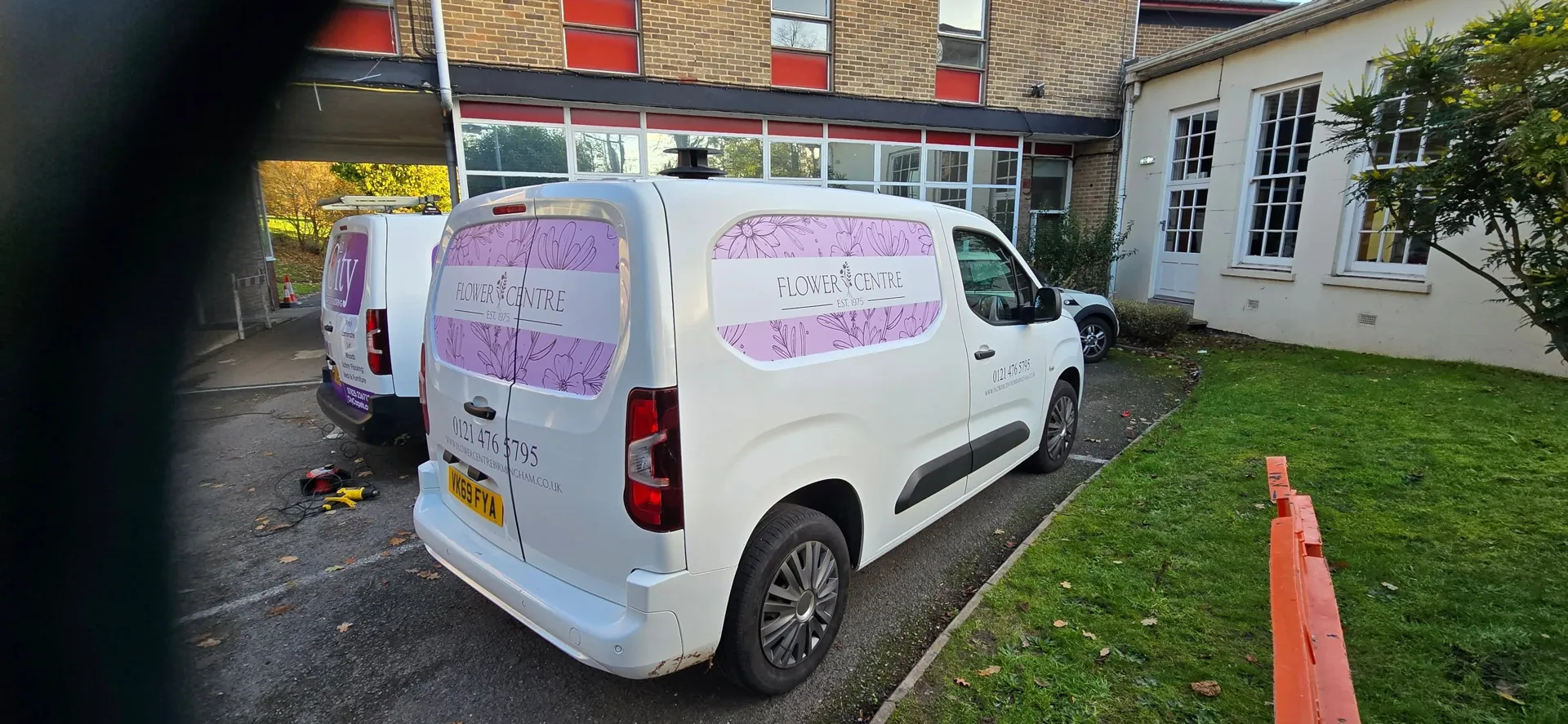 Van with rear-door and side-window graphics for a flower centre, outside the Bournville studio