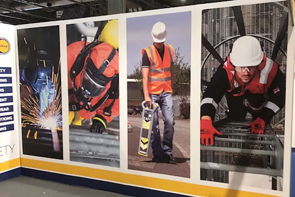 Printed hoarding panels showing site-safety imagery along a construction walkway