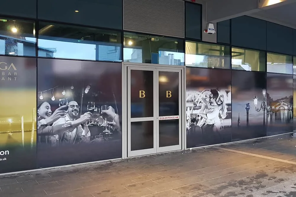 Full-height printed window graphics across a bar frontage