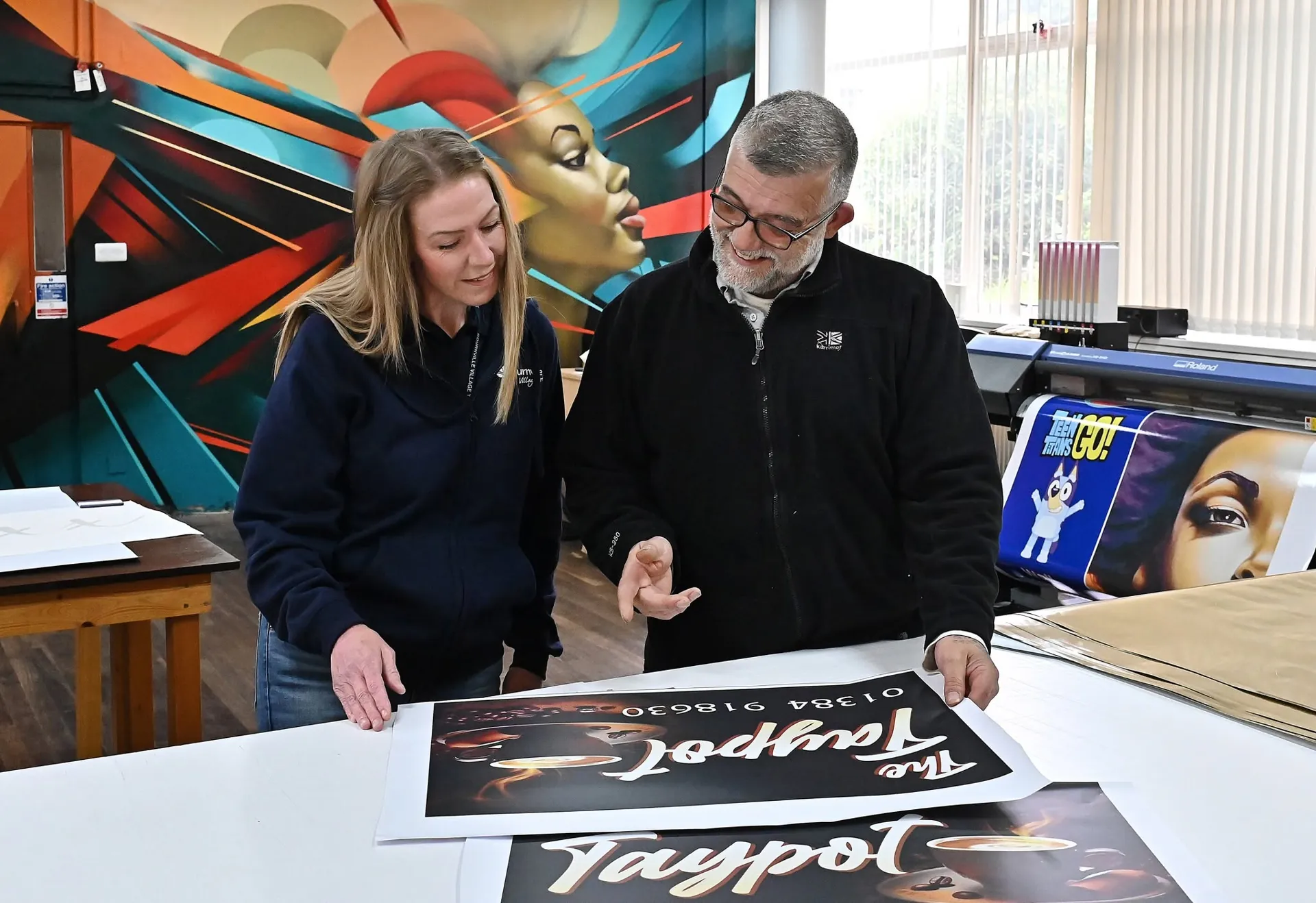 Abbey Signs team reviewing printed proofs on the studio bench