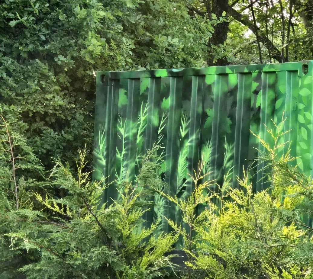 Close-up of a container wrapped in printed foliage, disappearing into the hedgerow