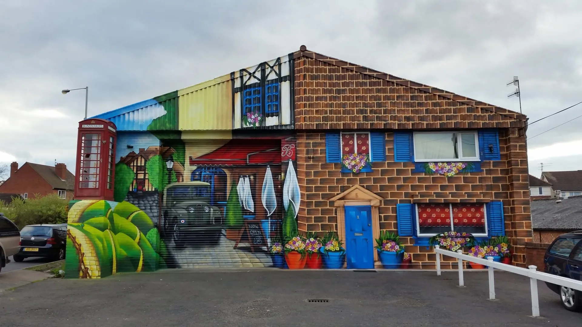 Painted trompe-l'oeil mural turning a plain gable into a brick cottage with shutters, flower boxes and a red phone box